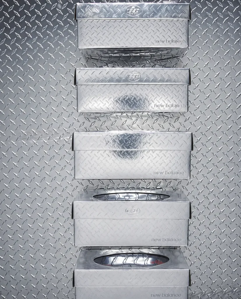 Stack of five silver metallic New Balance shoeboxes on diamond plate metal background, with some revealing sneakers inside