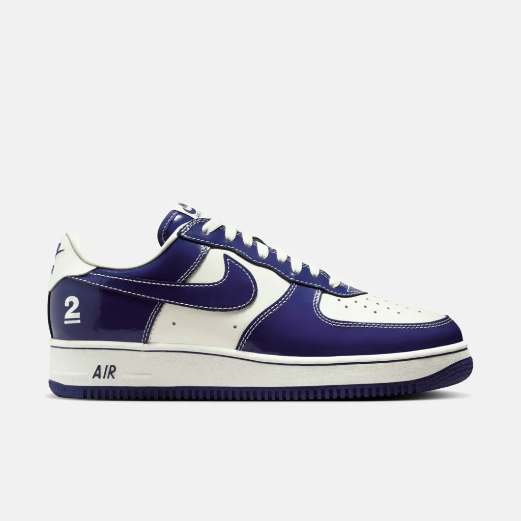 Low-top Nike shoe in a clean white and deep royal blue colorway, featuring smooth leather panels with contrast stitching and a matching blue Swoosh. The design includes perforations on the toe box, a white midsole with “AIR” branding, and a blue outsole, while a subtle “2” detail appears on the heel, adding a distinctive graphic touch to the classic silhouette