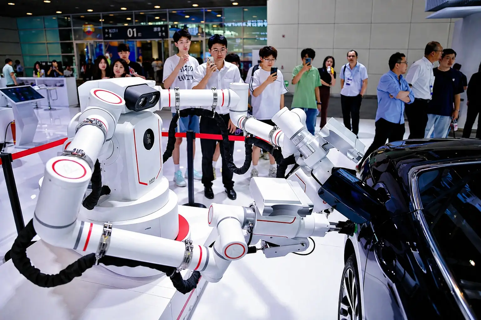 Industrial robotic arms performing automated tasks on a vehicle at Auto China 2026, demonstrating AI-driven manufacturing technology as attendees watch and record the live demonstration