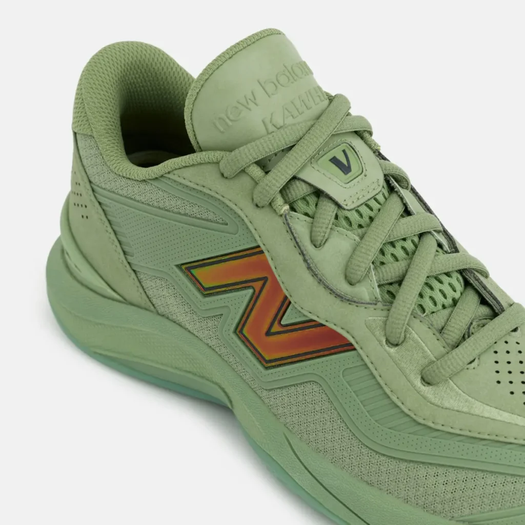 New Balance KAWHI V basketball shoe in monochrome green with mesh upper, structured overlays, and iridescent “N” logo detail on the side panel