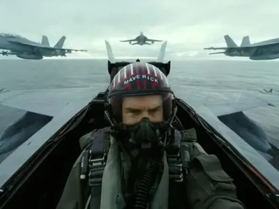 Cockpit-mounted view of Maverick piloting a fighter jet over open water, flanked by multiple aircraft in tight formation, capturing the high-speed realism and practical aerial choreography of Top Gun: Maverick