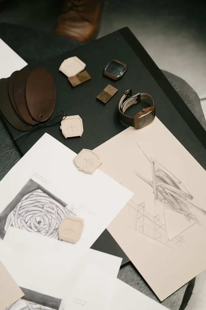 Alto Art 01 watch displayed alongside architectural sketches, material samples, and design prototypes on a studio table