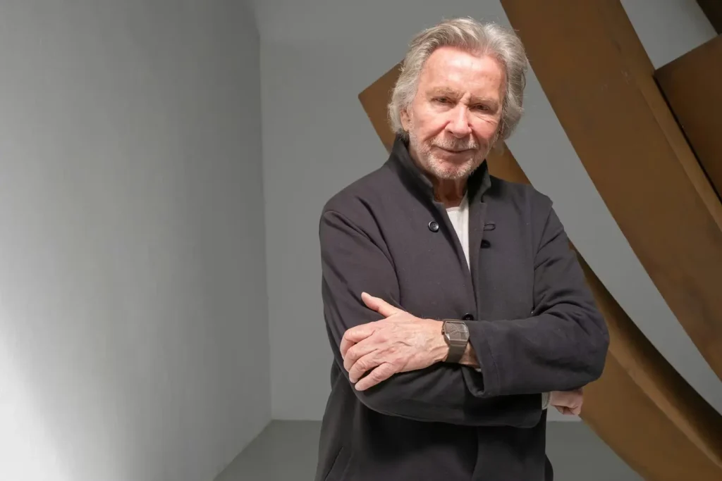 Primary Alt Text (Editorial) Portrait of Bernar Venet wearing the Alto Art 01 watch, standing before one of his large-scale steel arc sculptures