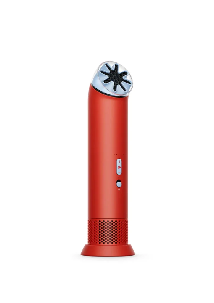 Compact handheld cooling device by Dyson in a matte red cylindrical design, featuring a precision airflow nozzle with a star-shaped outlet, front control buttons, and a perforated base for airflow intake, representing the HushJet Mini Cool fan