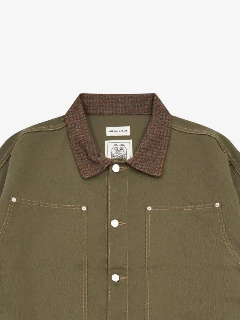 Close-up of Estudio Niksen Carpenter Collar Jacket in khaki featuring a textured checkered carpenter collar, front button closure, contrast stitching, and large square patch pockets in durable cotton canvas