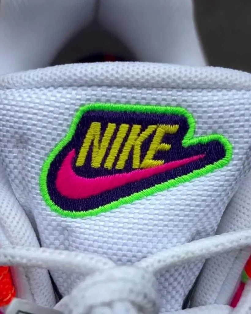 Close-up of Nike Air Max 95 Woven tongue featuring embroidered Nike logo in yellow and pink with neon green outline on white textured mesh background
