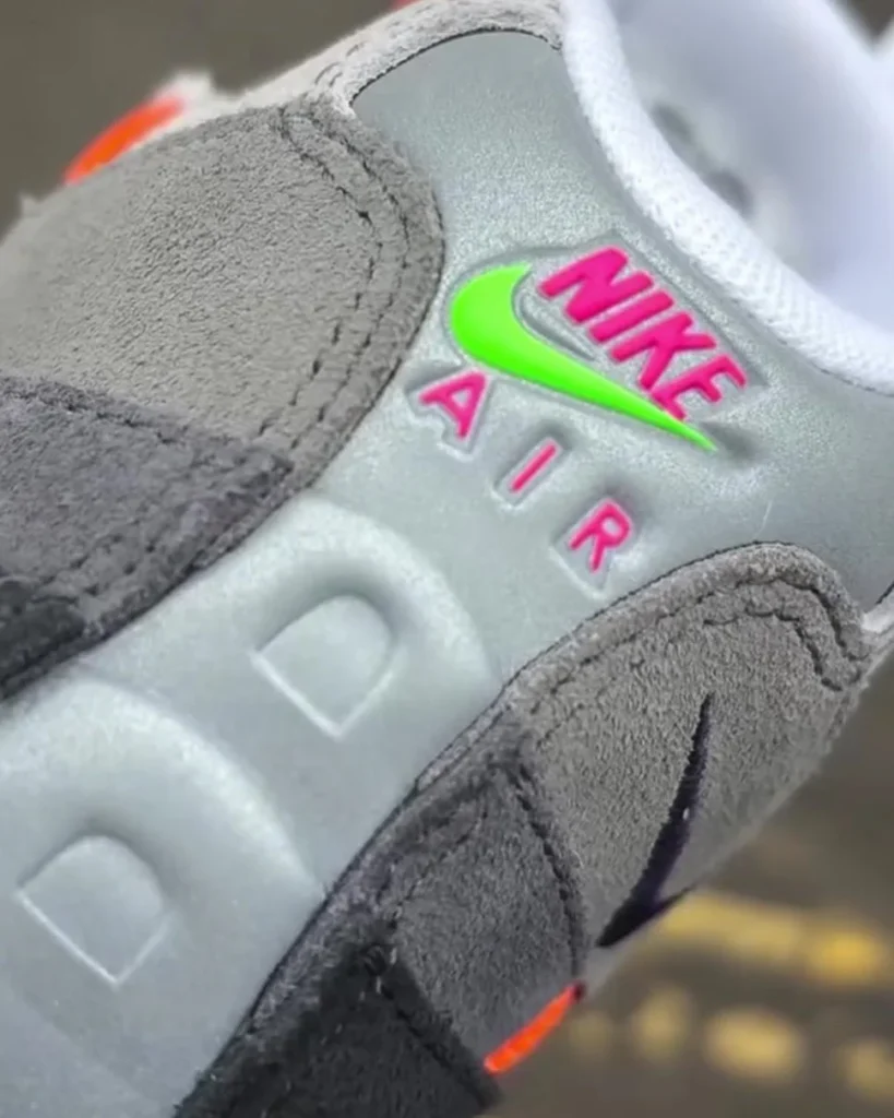 Close-up of Nike Air Max 95 Woven heel featuring embossed Nike Air branding with neon green swoosh and pink lettering on grey textured panel with suede overlays