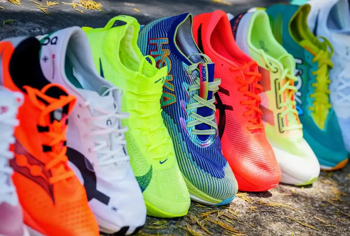 Collection of 2026 supershoes from Hoka, Nike, On and more in bright neon colors lined up outdoors