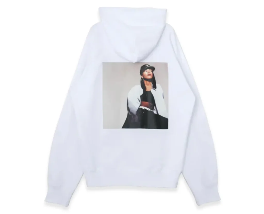 White sacai hoodie featuring a centered back print portrait of Aaliyah in a cap, presented against a clean, minimal studio backdrop