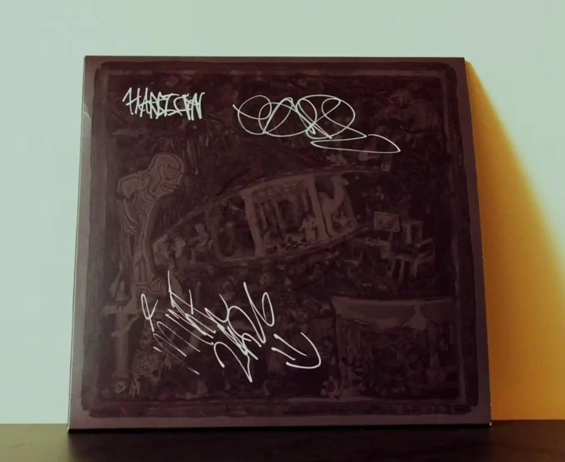 Close-up of the POMPEII / UTILITY Stone Island Sound edition vinyl sleeve featuring a darkened, black overlay artwork with layered abstract imagery and white handwritten-style signatures across the surface