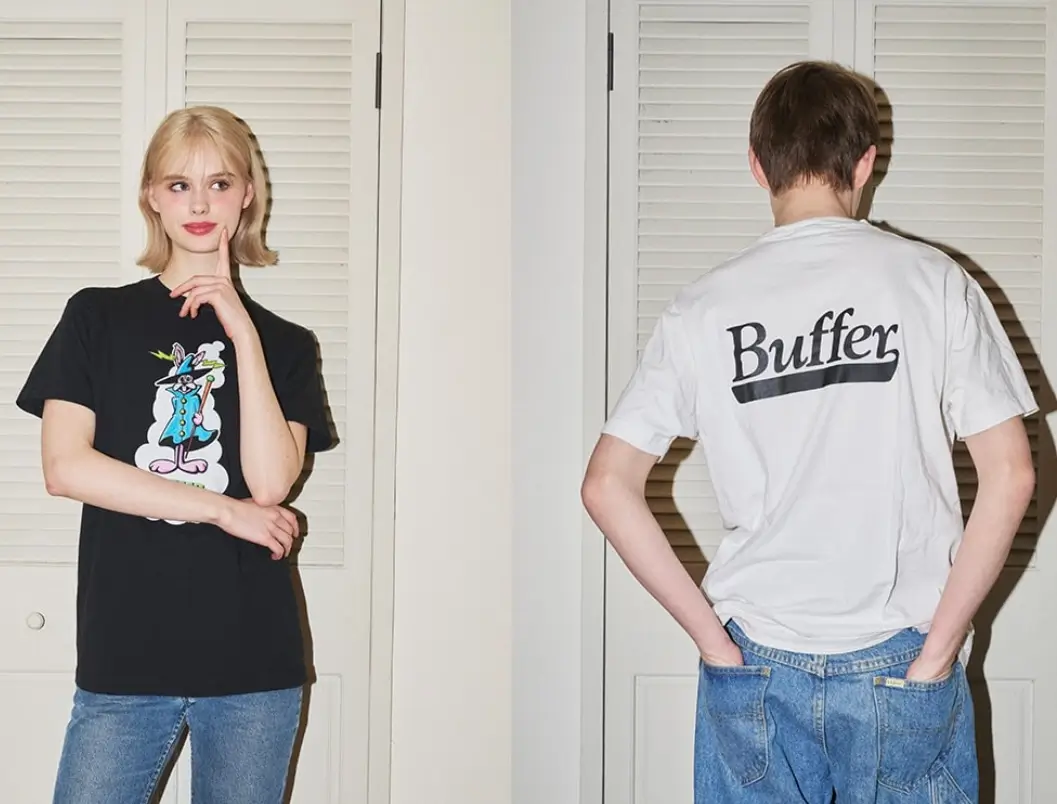 Two models styled in Buffer T-shirts—one wearing a black tee with a playful illustrated character graphic, the other shown from the back in a white tee