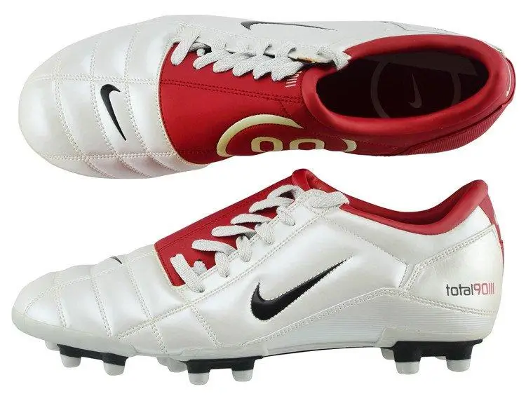 90 White leather football boots with a quilted forefoot and red midfoot panel, featuring black Swooshes, molded studs, and a classic Total 90-inspired design shown from top and side views