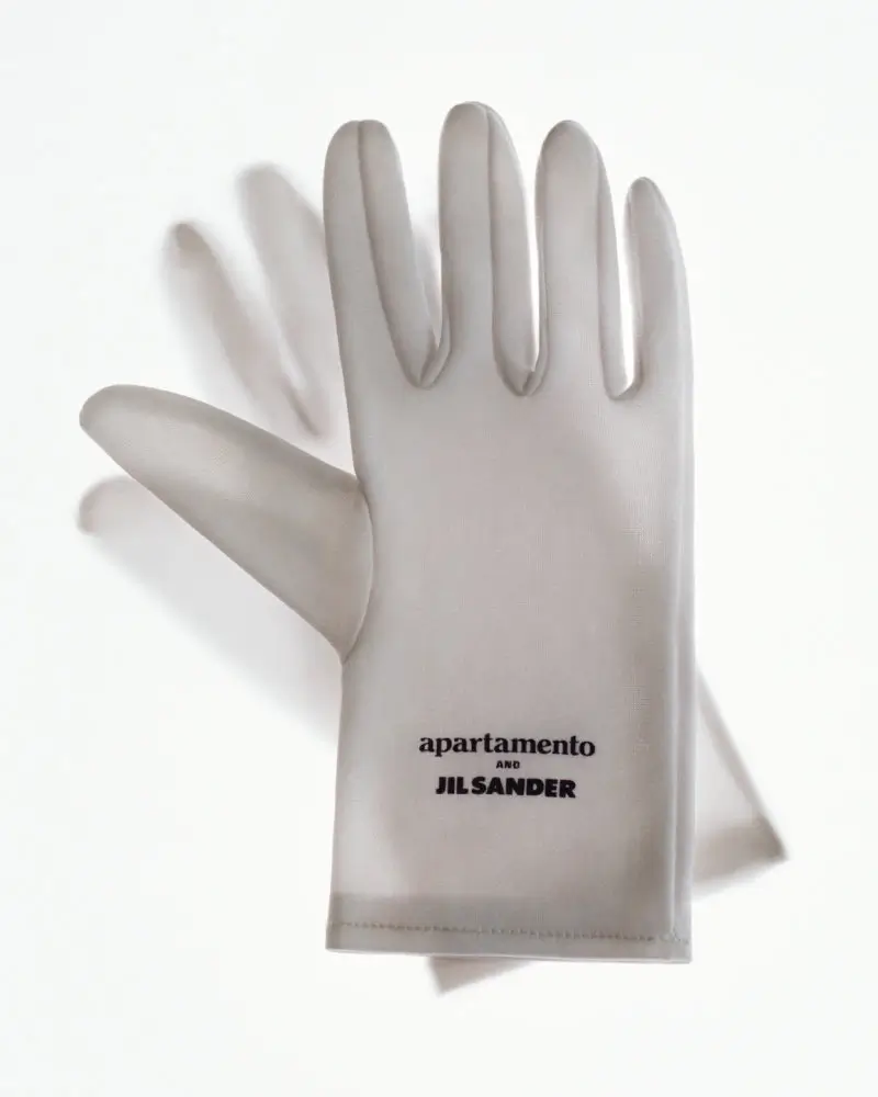 Apartamento x Jil Sander minimal glove featuring a smooth, translucent white material with subtle texture and clean silhouette, marked with understated black branding, reflecting the collaboration’s focus on purity, utility, and refined domestic aesthetics