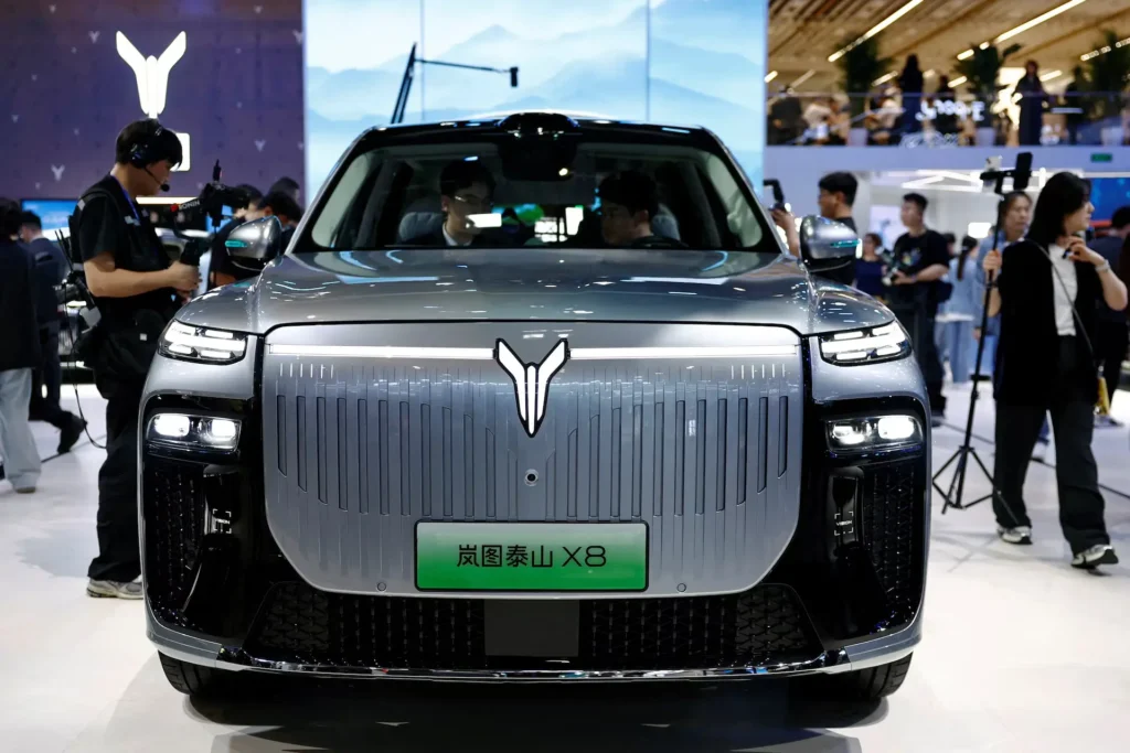 Front view of a Voyah Zhiyin X8 electric SUV displayed at Auto China 2026, featuring a vertical-lined grille design, illuminated emblem, split LED headlights, and attendees photographing the vehicle in a busy exhibition hall