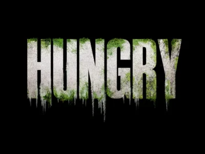 Bold, distressed title “HUNGRY” centered on a black background, the letters textured like cracked stone with mossy green growth and dripping, decay-like streaks, evoking horror and organic unease