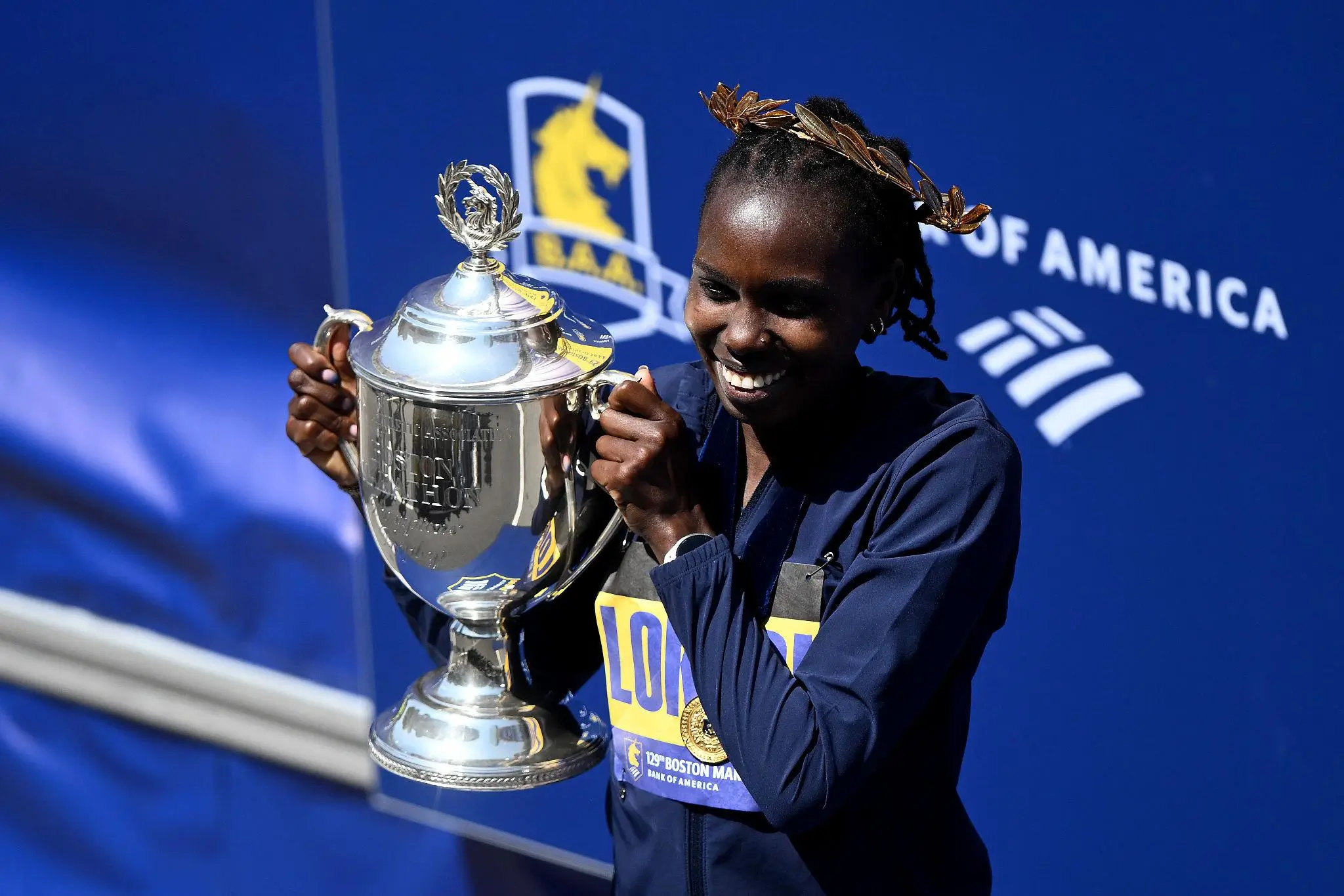 Sharon Lokedi proudly holding the Boston Marathon trophy after winning the 2026 race