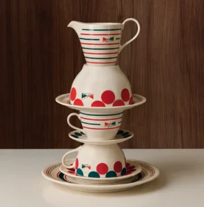 Stacked Marni x Serax ceramic tableware featuring a striped milk jug, polka-dot bowls, cups, and saucers arranged in a sculptural composition against a wooden backdrop