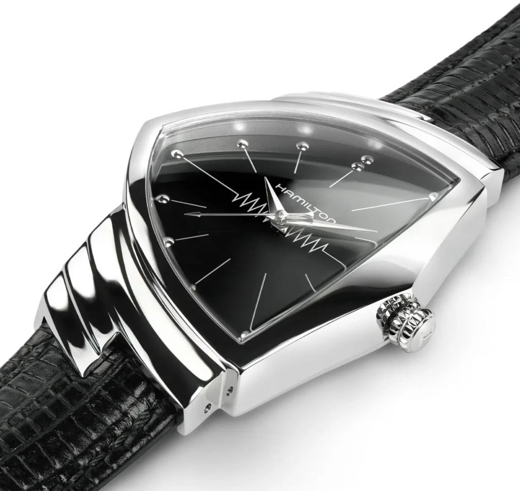 Close-up of the Hamilton Ventura Quartz H24411732 highlighting its polished stainless steel triangular case, black dial with minimalist indices, and distinctive zigzag seconds detail, paired with a textured black leather strap and crown at three o’clock