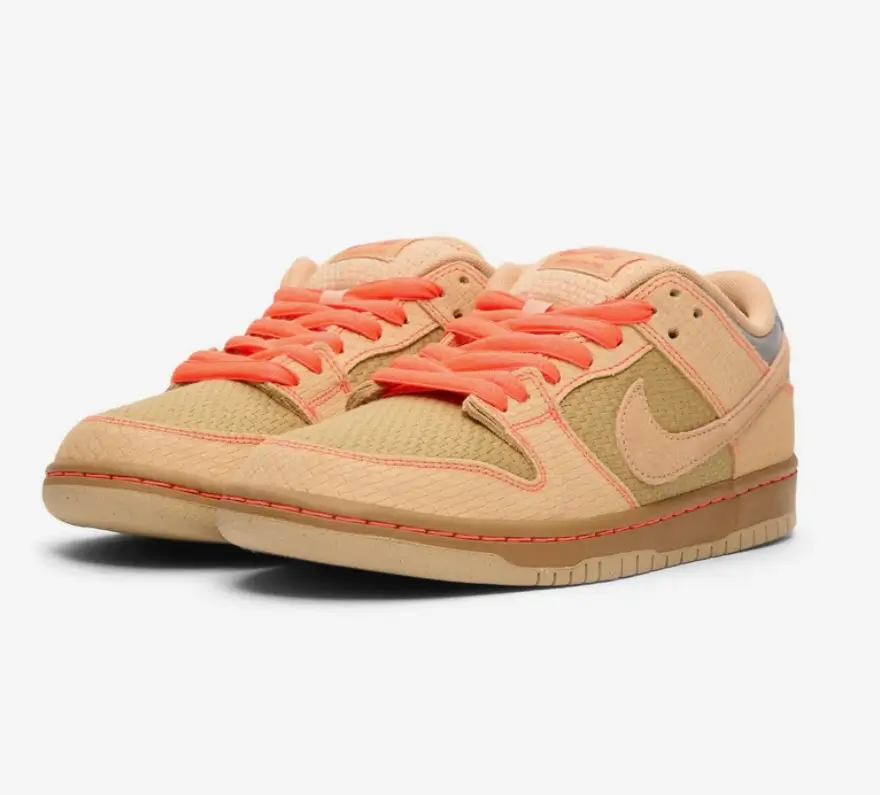 Front three-quarter view of the Nike SB Dunk Low Pro in Vachetta Tan–Parachute Beige, featuring woven canvas panels, tonal suede overlays, bright coral laces with matching contrast stitching, a subtle Swoosh, and a gum rubber sole