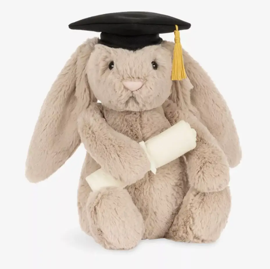 Jellycat Bashful Bunny Graduation Outfit 31cm plush shown front-facing, with soft beige fur, a black graduation cap with gold tassel, and holding a rolled fabric diploma across its lap