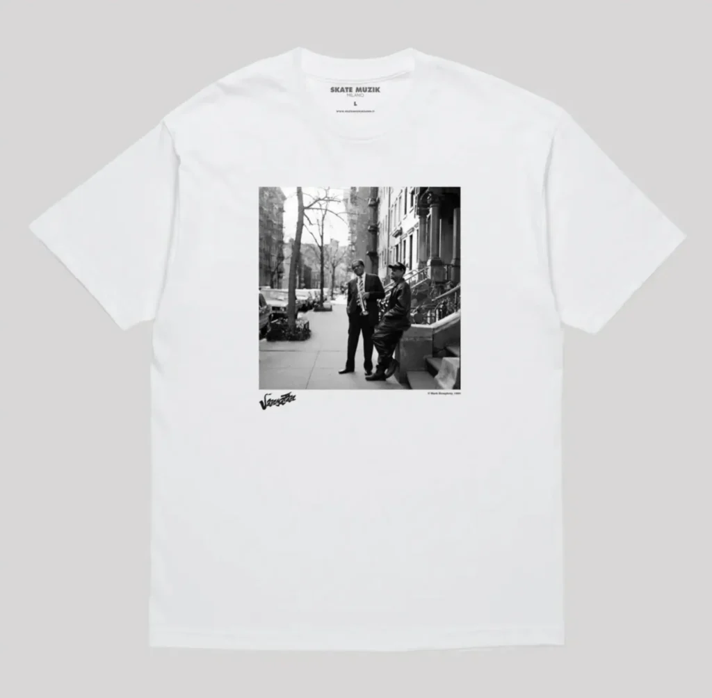 White Skate Muzik t-shirt with vintage black and white street photography print on the front. Trumpet player and companion in NYC setting — premium Milan skate culture merch