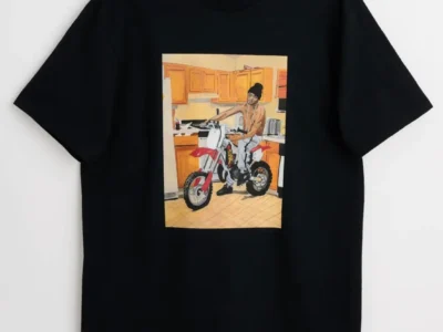 Black Skate Muzik t-shirt with illustrated scene of a rider on a dirt bike in a kitchen. Premium Milan skate culture merch, artistic 2026 drop