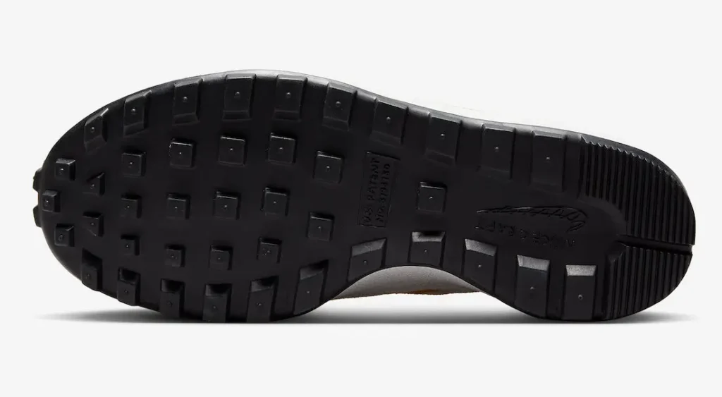 Full outsole view of the Tom Sachs x Nike NikeCraft General Purpose Shoe “Bricolage,” featuring a rugged black rubber tread with square lugs, flex grooves, and NikeCraft branding embedded in the midfoot for durable, all-terrain traction