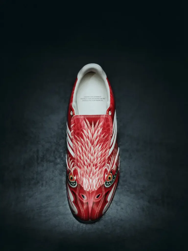 Top-down view of a red Y-3 F50 TUNIT shoe featuring an eagle-inspired graphic across the upper, set against a dark textured background