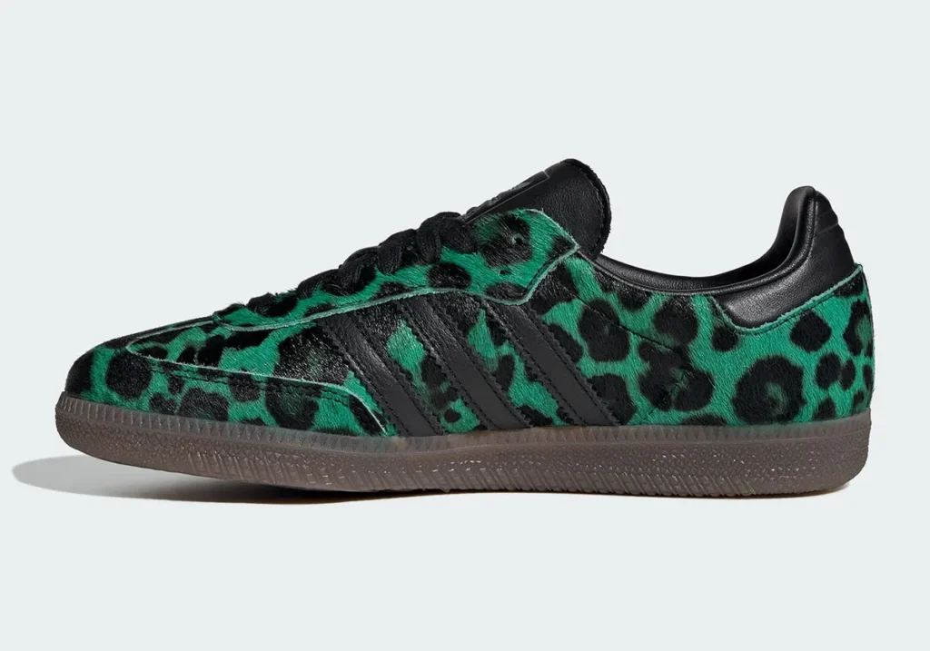 Side profile of a low-top shoe featuring a green-and-black leopard print pony hair upper. The shoe includes black leather three-stripe overlays, black laces, and a padded black heel tab. A semi-translucent gum sole runs along the base, while visible stitching and the textured hair finish highlight the elevated material construction