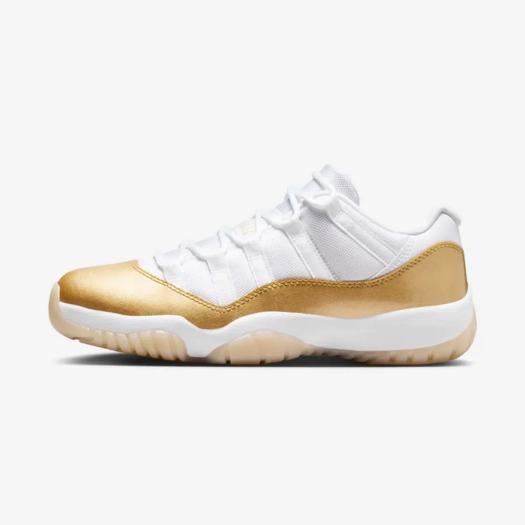White low-top shoe with a mesh upper and patent leather mudguard in metallic gold, featuring matching gold heel wrap, white laces and midsole, and a translucent gum outsole, presented in a clean side profile against a neutral background
