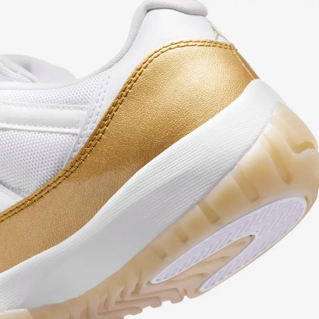 Close-up of the shoe heel showing a metallic gold patent leather wrap with visible stitching, a white textured midsole, and a translucent gum outsole with herringbone traction detail
