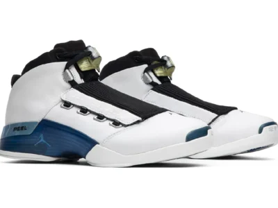 Pair of Air Jordan 17 “College Blue” shoe in white leather with blue midsole accents, black shrouds, metal eyelets, and translucent lace locks, shown in angled side view