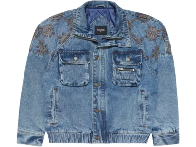 Light-wash denim jacket with a slightly cropped, boxy silhouette, featuring ornate sunburst-style embroidery across the shoulders and upper sleeves. The jacket includes dual chest flap pockets with metal button closures, an additional zip pocket on the right chest, and two vertical side pockets. Finished with a pointed collar, button-front closure, elasticated hem, and a quilted blue interior lining, giving it a structured yet worn-in, vintage-inspired look