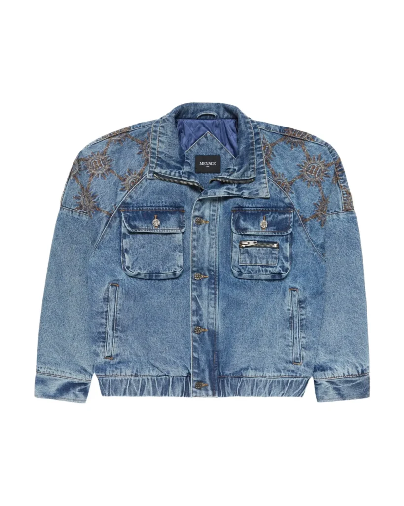 Light-wash denim jacket with a slightly cropped, boxy silhouette, featuring ornate sunburst-style embroidery across the shoulders and upper sleeves. The jacket includes dual chest flap pockets with metal button closures, an additional zip pocket on the right chest, and two vertical side pockets. Finished with a pointed collar, button-front closure, elasticated hem, and a quilted blue interior lining, giving it a structured yet worn-in, vintage-inspired look