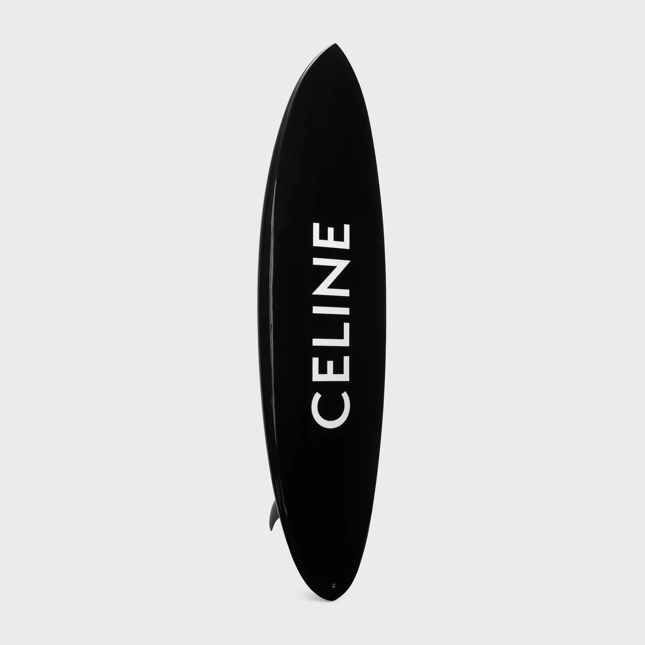 Black Celine surfboard with bold white logo centered on a clean, neutral background