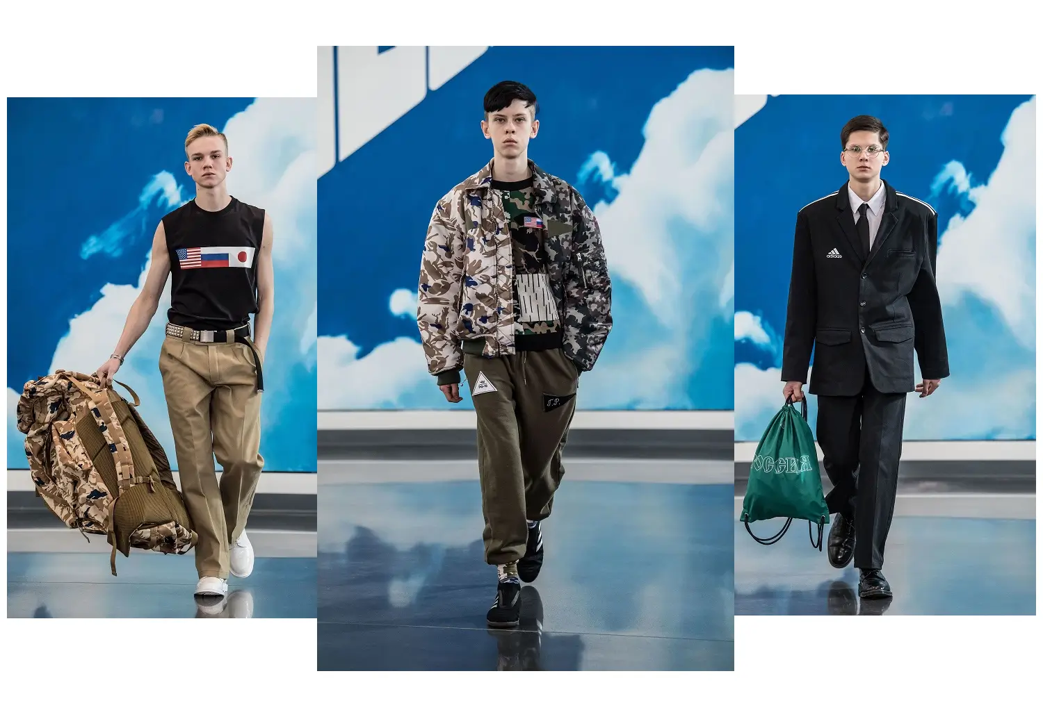 Triptych of three runway models walking against a sky-blue backdrop with cloud imagery. On the left, a model wears a sleeveless black top with flag graphics, beige trousers, and white sneakers, carrying a large camouflage duffel bag. In the center, a model is dressed in layered camouflage outerwear with olive joggers and black sneakers, presenting a utilitarian, military-inspired look. On the right, a model wears a structured black suit with an adidas logo, white shirt, and tie, carrying a green drawstring bag with Cyrillic text, blending formal tailoring with sportswear elements