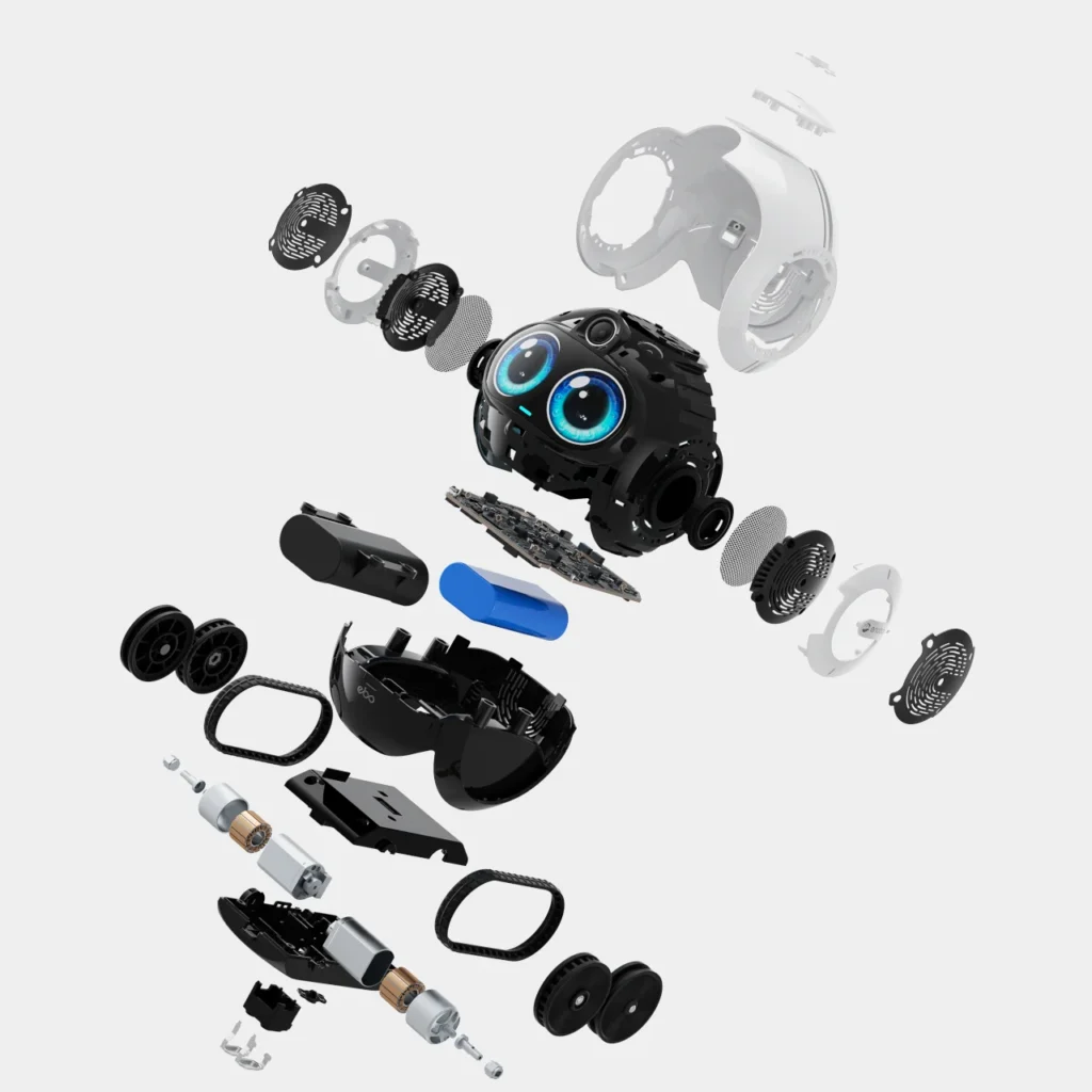 An exploded-view rendering of a compact companion robot reveals its internal components suspended in midair, including the central body with animated blue digital eyes and camera module, layered circuit boards, speaker assemblies, outer shell panels, wheels, treads, and motor units—presented against a clean white background to showcase its intricate engineering and modular design