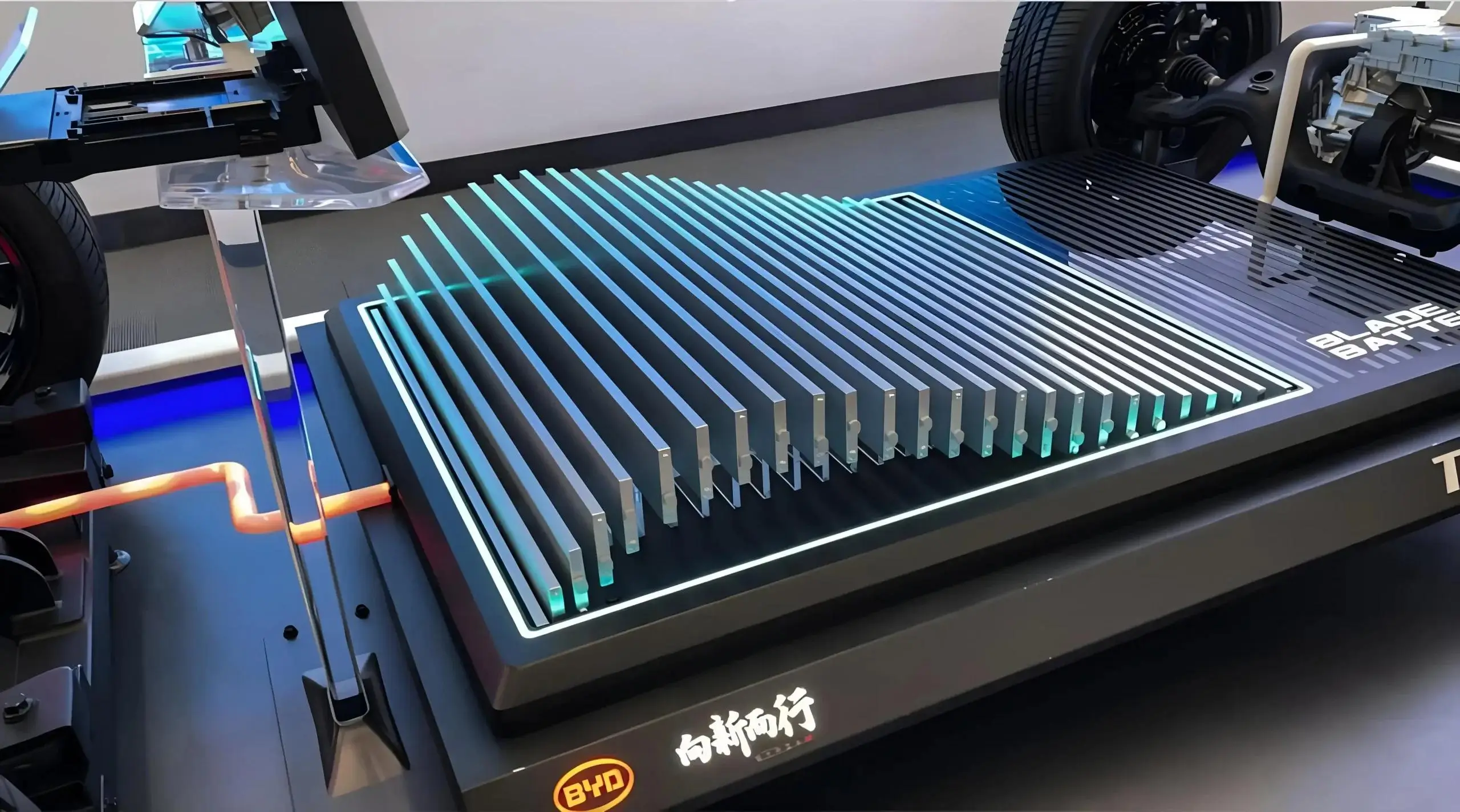 Close-up of a BYD Blade battery display at Auto China 2026, showing a flat structural battery pack with exposed cooling fins, illuminated energy flow accents, and surrounding drivetrain components in a technical exhibition setup