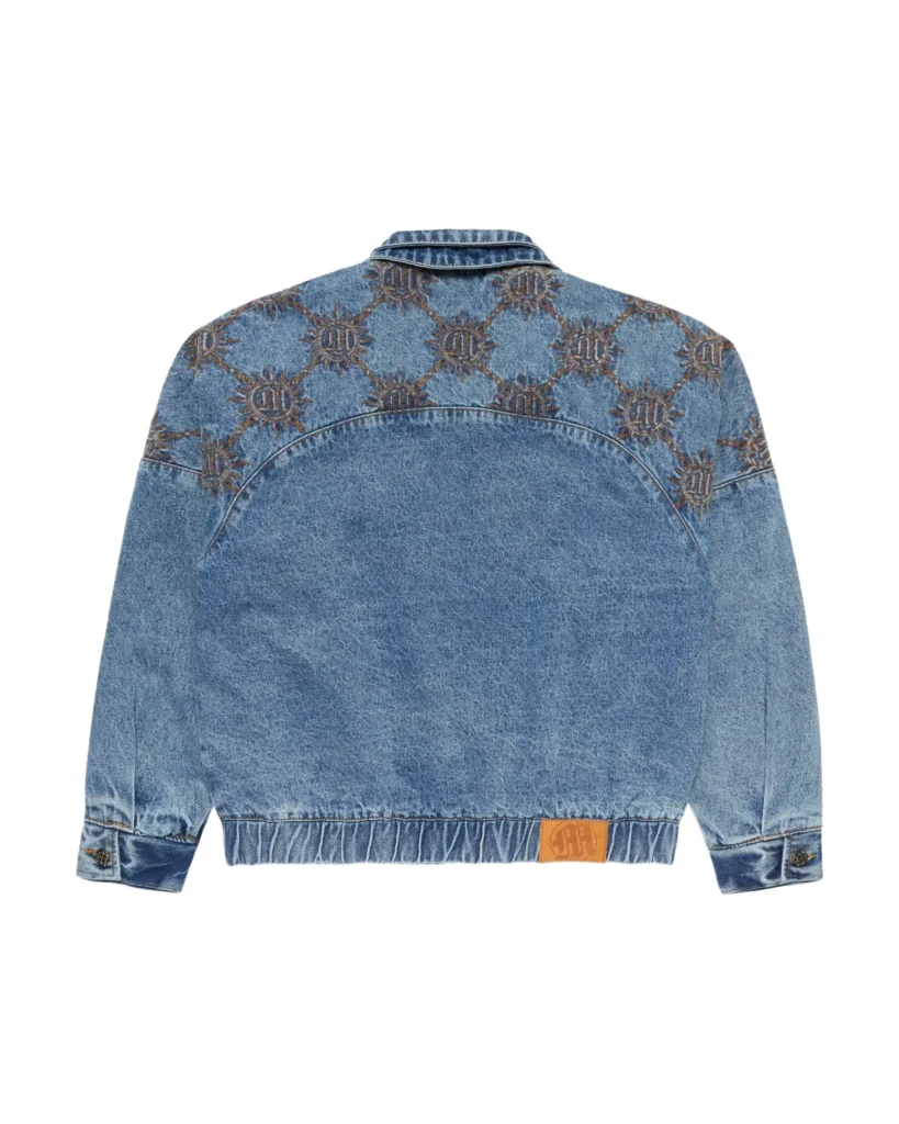 Back view of a light-wash denim jacket with a slightly cropped, relaxed fit, featuring an all-over sunburst-style embroidered pattern across the upper back and shoulders. The lower back remains clean with subtle fading, while a curved yoke seam adds structure. Finished with an elasticated hem, buttoned cuffs, and a small tan leather logo patch near the waistband, balancing decorative detailing with a vintage workwear feel