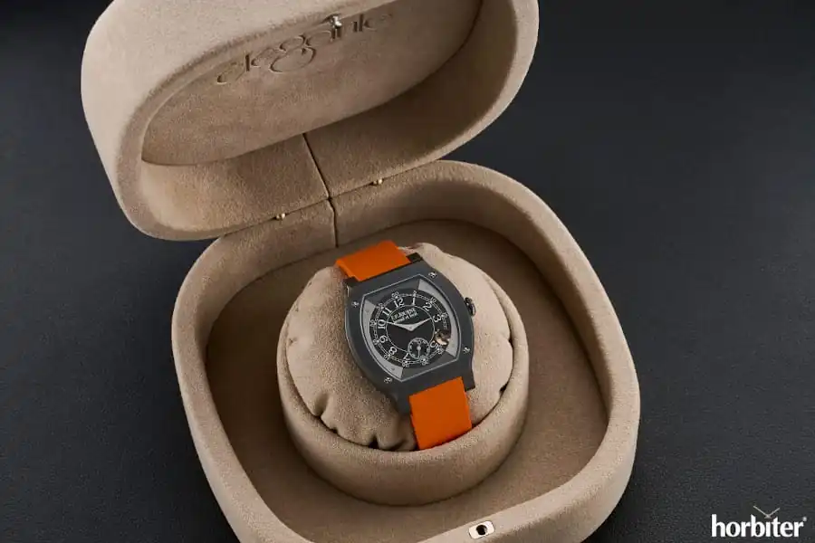 F.P. Journe Élégante 48 Titalyt titanium tortue-shaped watch with dark dial, small seconds subdial, visible motion detector aperture, and orange rubber strap displayed inside beige presentation box
