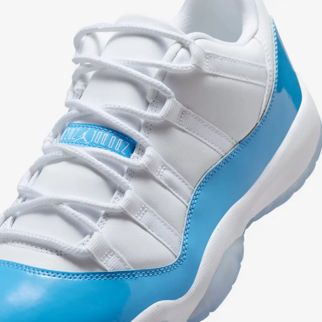Close-up of Air Jordan 11 Low UNC 2026 showing white leather upper, rope lacing system, and Carolina blue patent leather mudguard