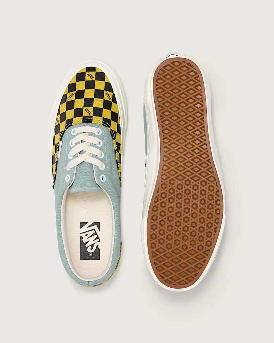 Top and bottom view of a Vans Era shoe featuring a yellow-and-black checkerboard toe panel with small Vans logos, light blue canvas upper, white laces, and a classic brown waffle outsole
