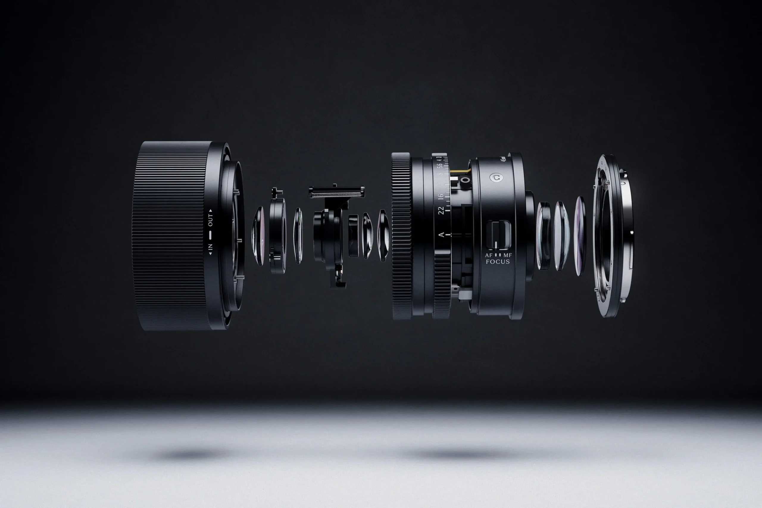 An exploded view of a camera lens reveals its internal components suspended in sequence, with individual glass elements, rings, and mechanical parts aligned horizontally against a dark gradient background