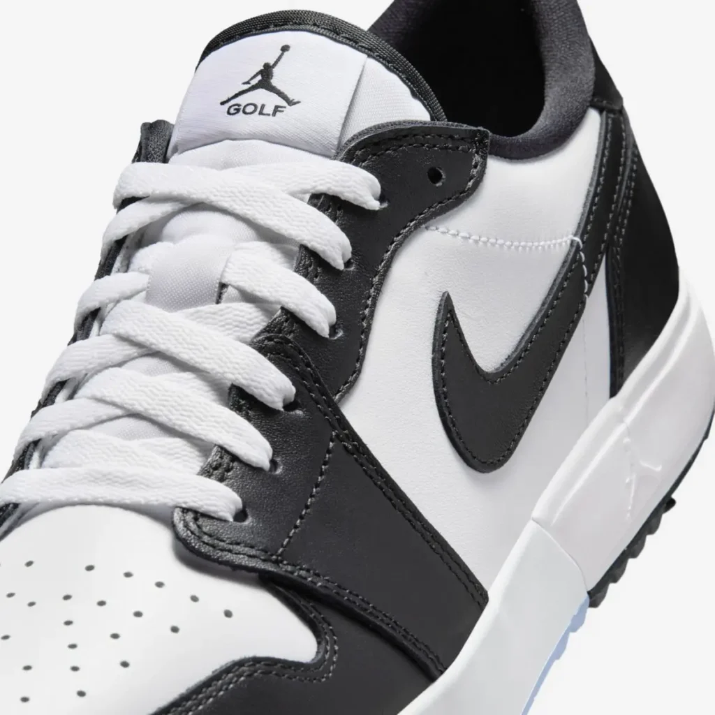 Close-up of Air Jordan 1 Low Golf Spiked Concord showing white leather upper, black overlays and Swoosh, white laces, and Jumpman Golf logo on the tongue