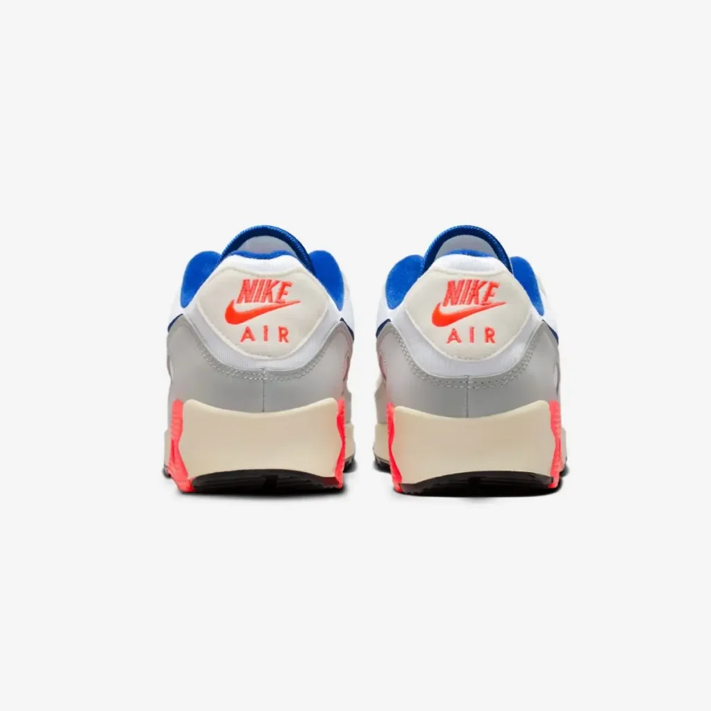 Rear view of the Nike Air Max 90 “Ultramarine” pair, showing light grey heel panels, off-white heel tabs with red Nike Air branding, blue collar lining, and a cream midsole with red accents wrapping the heel