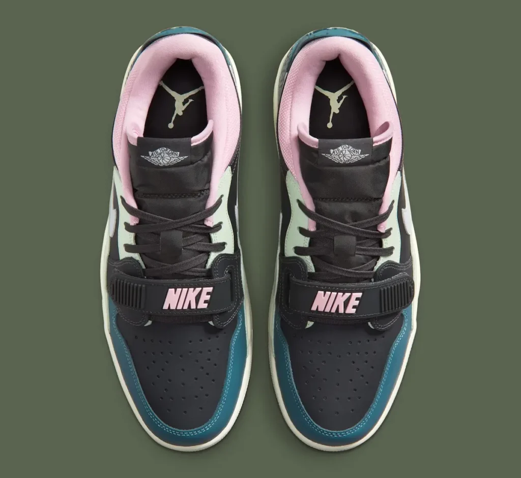 A top-down view of a pair of Nike Air Jordan low-top shoe, showcasing their symmetrical layout and layered color blocking. The shoes feature a black perforated toe box with teal mudguards, complemented by mint green side panels and a soft pink padded collar lining. Black laces run through a structured upper, secured by a forefoot strap with raised “NIKE” branding in pink. The tongues display the Air Jordan Wings logo, while the insoles reveal contrasting Jumpman logos, emphasizing the blend of heritage basketball design and contemporary styling