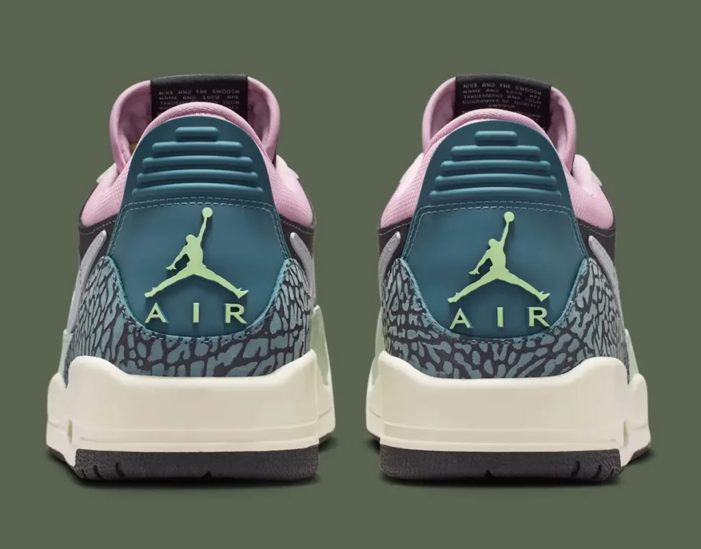 A rear view of a pair of Nike Air Jordan low-top shoe, highlighting the heel design and branding details. The heels feature a teal panel with a contrasting Jumpman logo above “AIR” lettering in a light green tone. Surrounding the heel is a textured elephant-print overlay, adding depth and a classic Jordan aesthetic. The padded collar is lined in soft pink, while the off-white midsole and dark outsole ground the design, blending heritage basketball cues with a modern, color-blocked finish