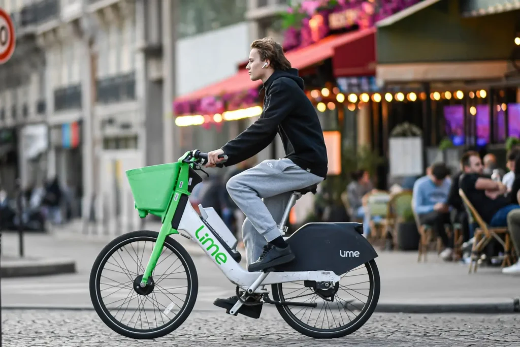 Rider commuting on a Lime electric bike through a city street, featuring a low step-through frame, front basket, and accessible design suited for everyday urban travel