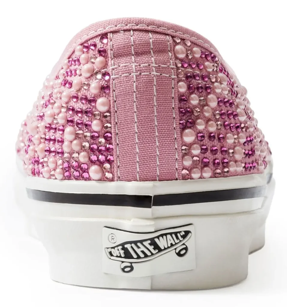 Rear view of pink Vans Authentic shoe covered in rhinestones and pearl-like studs, featuring a stitched heel panel and off-white sole with the signature “Off The Wall” logo