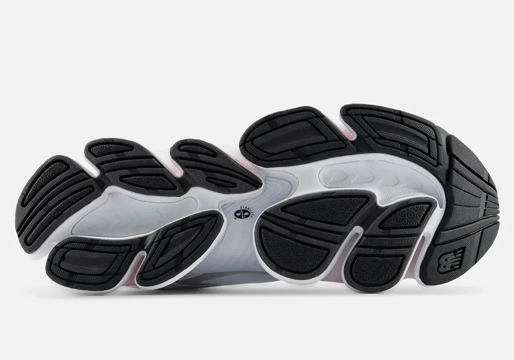 A detailed bottom view of a running shoe outsole, showing segmented black rubber traction pods and white midsole sections with sculpted channels designed for flexibility and gripA detailed bottom view of a running shoe outsole, showing segmented black rubber traction pods and white midsole sections with sculpted channels designed for flexibility and grip